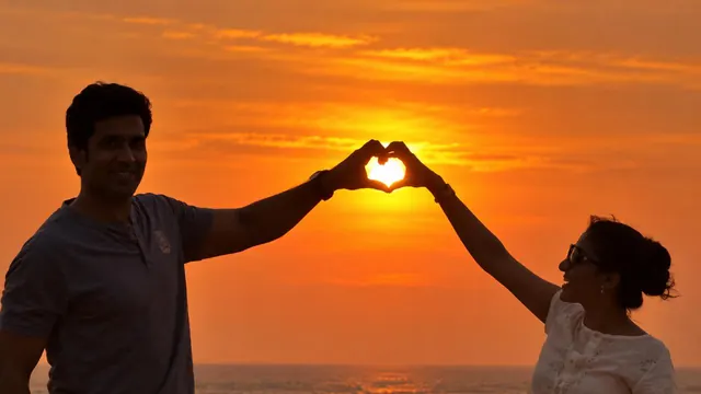 Couple making a heart at sunset on Poovar beach