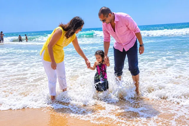 Family playing in the waves at Poovar golden sand beach