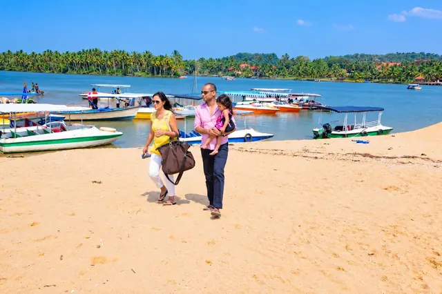 Guests walking on the Poovar sand bar with boats behind